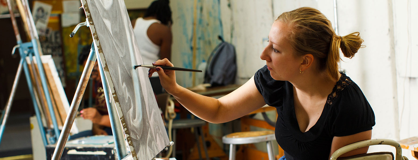 Female art student at easel with paint brush in hand